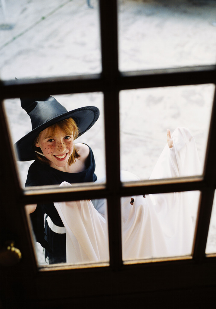 Girl standing at the door wearing a witches costume trick or treating.