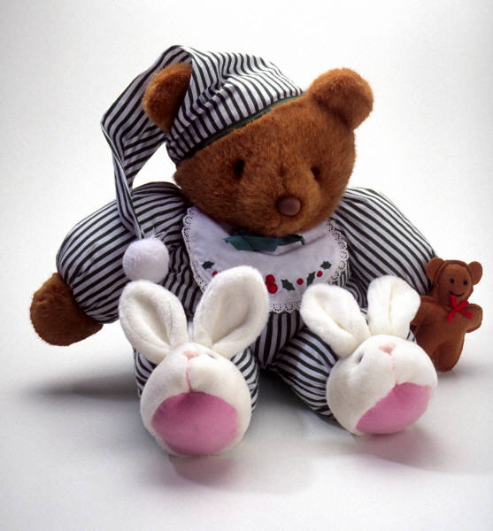 Teddy bear wearing pajamas and bunny slippers.